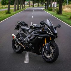 a black motorcycle is parked on the side of the road in front of some trees