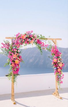 an outdoor ceremony setup with pink flowers and greenery