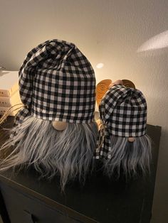 two hats are sitting on top of a black and white tableclothed hat with long grey hair