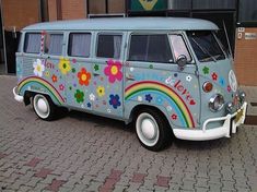 an old vw bus painted with flowers and rainbows is parked in front of a building