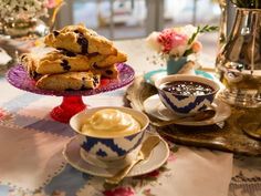 a table topped with plates and cups filled with dessert next to a vase full of flowers