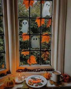 a window decorated for halloween with pumpkins, cookies and ghost decorations on the windowsill