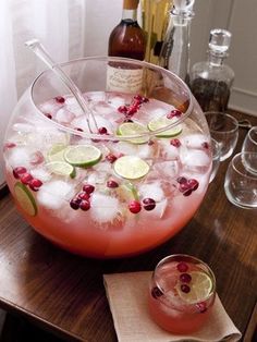 a large bowl filled with ice and garnish next to two glasses on a table