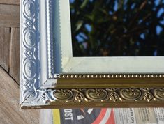 an ornate gold and silver framed mirror on a wooden wall