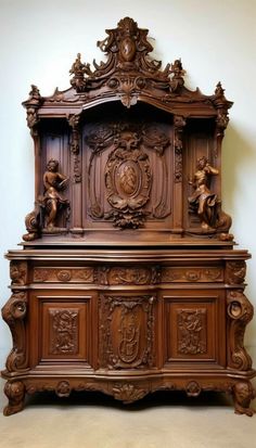 an ornate wooden cabinet with carvings on the front and sides, sitting against a white wall