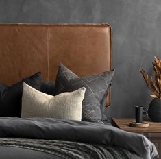 a brown leather headboard on a bed next to two vases with dry plants