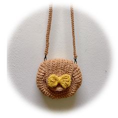 a crocheted purse with a smiley face on it's side hanging from a wall