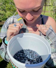 a woman is eating blueberries out of a bucket