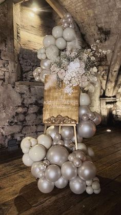 a bunch of balloons that are on top of a wooden table in a room with stone walls