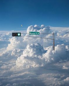 a street sign that reads moon st and is above the clouds with a half moon in the distance