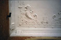 a white wall with an ornate design on the side and brick floor next to it