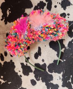 a pink and blue hair piece on top of a cow print rug