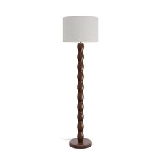 a floor lamp with a white shade on the top and brown base, standing against a white background