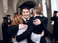 two students hugging each other in graduation gowns and caps at the end of a hallway