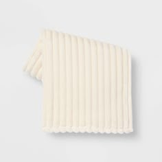 the rib knit scarf in ivory is folded on top of a white surface and has fringes