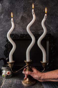 a person lighting candles on a table with other items in front of them and a black background