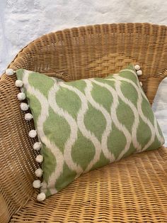 a green and white pillow sitting on top of a wicker chair