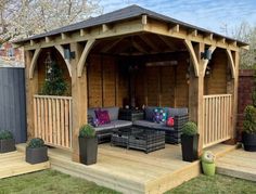 a wooden gazebo sitting on top of a lush green field