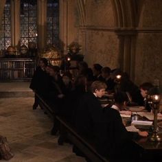 a group of people sitting at desks in a church with candles on the table