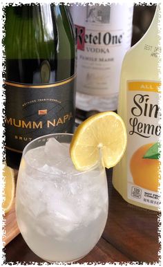 an alcoholic drink with ice and lemon wedges next to two bottles of rumma napa