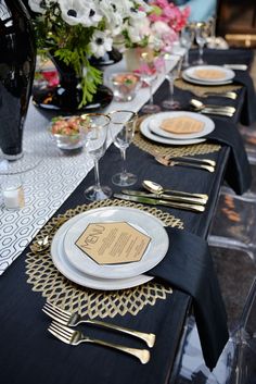 the table is set with black and gold place settings