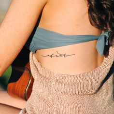 a woman sitting in a chair with her back turned to the camera and tattoos on her stomach