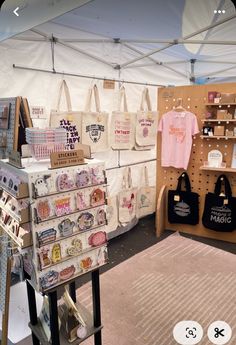 there are many bags and t - shirts on display in the store's booth