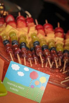 an assortment of fruit on sticks in a bowl