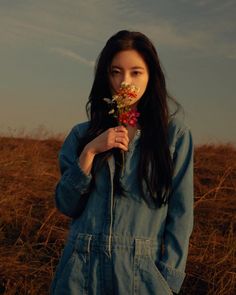 a woman standing in a field holding flowers