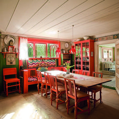 a dining room with orange walls and wooden chairs, an oven in the back ground