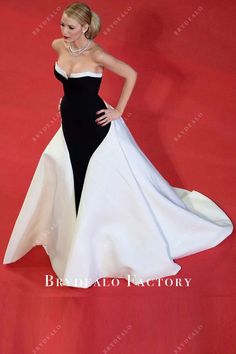 a woman in a black and white dress standing on a red carpet with her hands on her hips