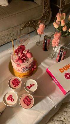 there is a cake with pink icing on the table next to other cupcakes