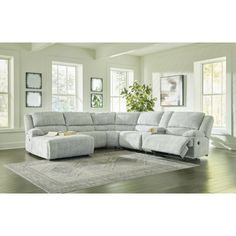 a living room with a large sectional couch and ottoman in it's center area