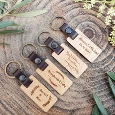 three wooden keychains sitting on top of a piece of wood next to plants