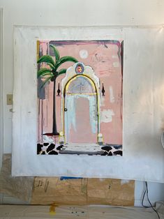 a painting is hanging on the wall in front of a door with a palm tree