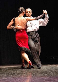 two people dancing on a stage with one holding the other's arm around his neck