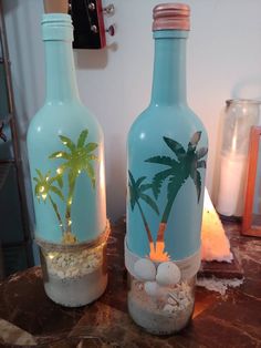 two blue bottles with palm trees on them sitting on a table next to each other