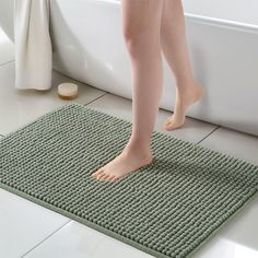 a person standing on a mat in front of a bathtub