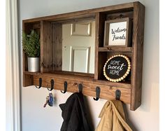 a mirror and coat rack with hooks on the wall next to a potted plant