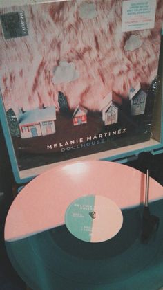 a record player sitting on top of a table next to a wall with a poster behind it