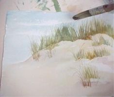 a painting of grass and sand on a white tablecloth with a brush in the foreground