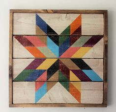 a multicolored wooden star is mounted on a white wall with wood planks