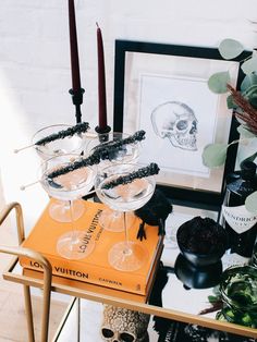 two wine glasses sitting on top of an orange box next to candles and other items