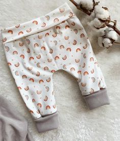 a baby's pants with rainbows and clouds on them next to cotton flowers