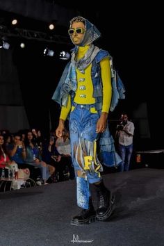 a man in yellow shirt and blue pants walking down the runway