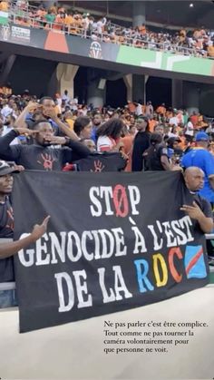 a group of people holding up a sign in front of a crowd at a soccer game