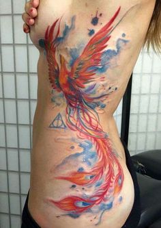 a woman's stomach with a colorful bird tattoo on the side, and watercolor splashes all over it