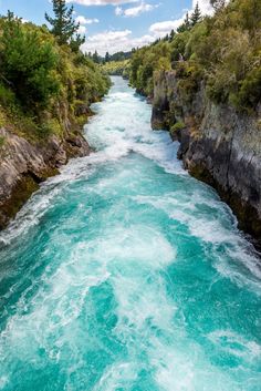 the water is very blue and green in this river that runs between two cliffs with trees on both sides