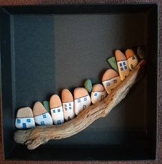 a group of small houses sitting on top of a wooden branch in a shadow box