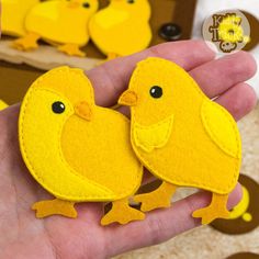 two yellow birds are sitting on the palm of a person's hand, with buttons in the background